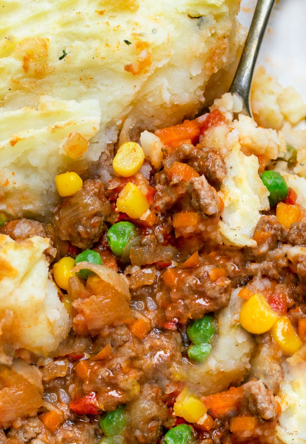 close up of shepherd's pie with mashed potatoes, ground lamb, carrots, corn and peas