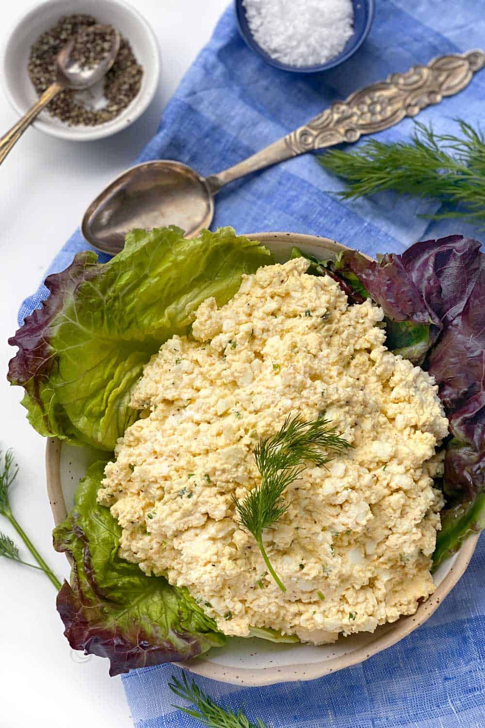 egg salad on lettuce leaves in a bowl with a sprig of dill in the middle