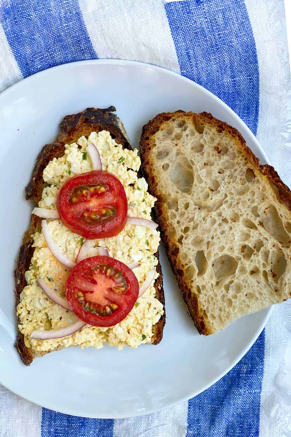 egg salad on toasted sour dough bread with red onions and sliced tomatoes