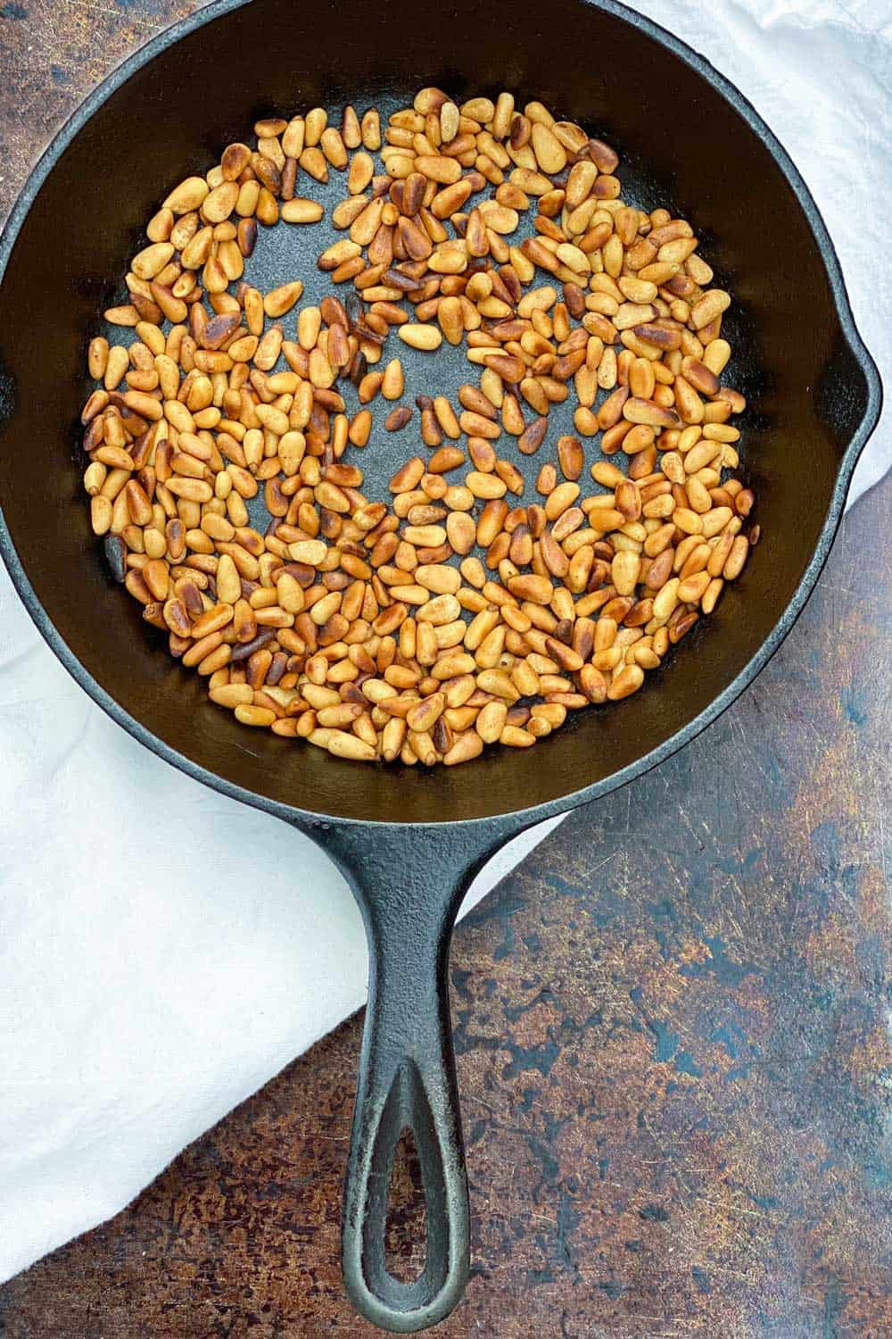 toasted pine nuts in a cast iron skillet