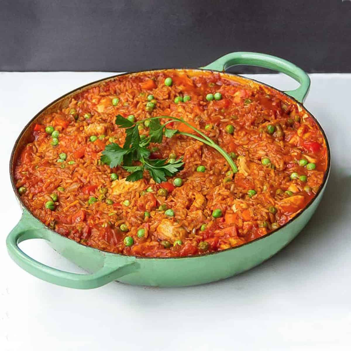 Jollof rice with chicken and peas in a shallow dutch oven.