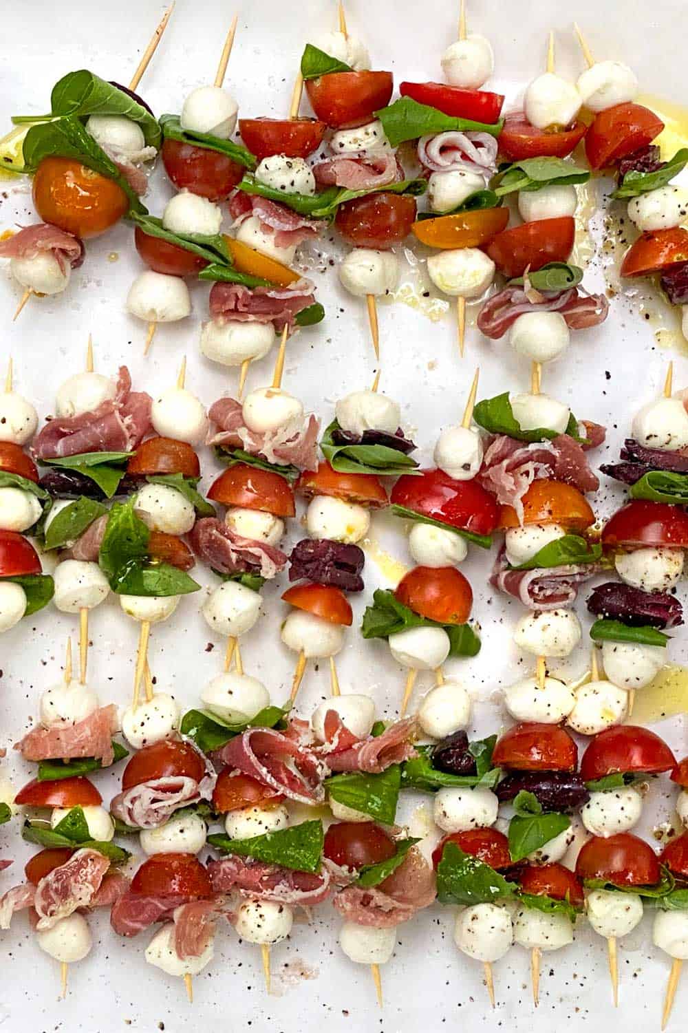 mini caprese skewers with mini mozzarella balls, cherry tomatoes and fresh basil leaves