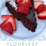 a slice of flourless chocolate truffle cake on a light blue plate, topped with sliced strawberries