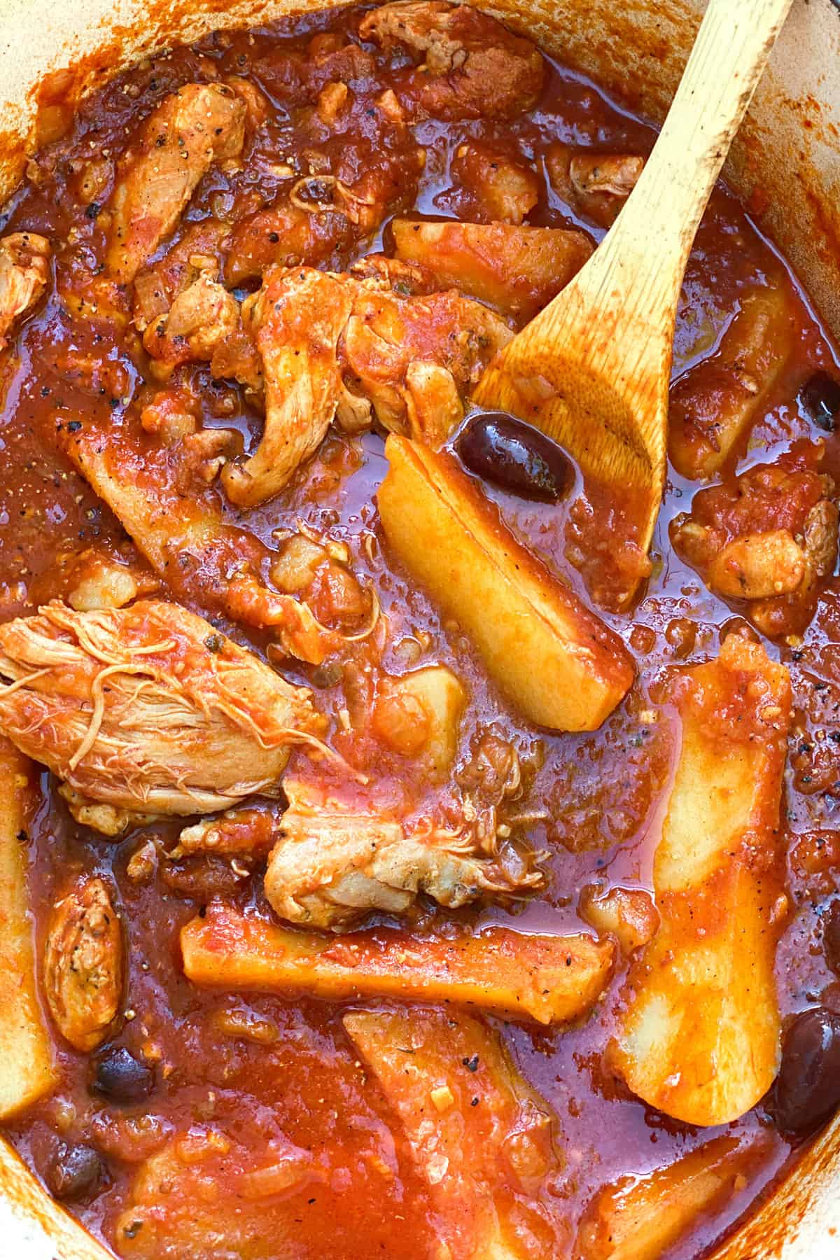 tender looking boneless chicken thighs and potato wedges in tomato sauce with black olives