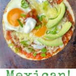 flour tortilla toped with beans, salsa, two fried eggs, sliced avocado, a blog of sour cream in the middle