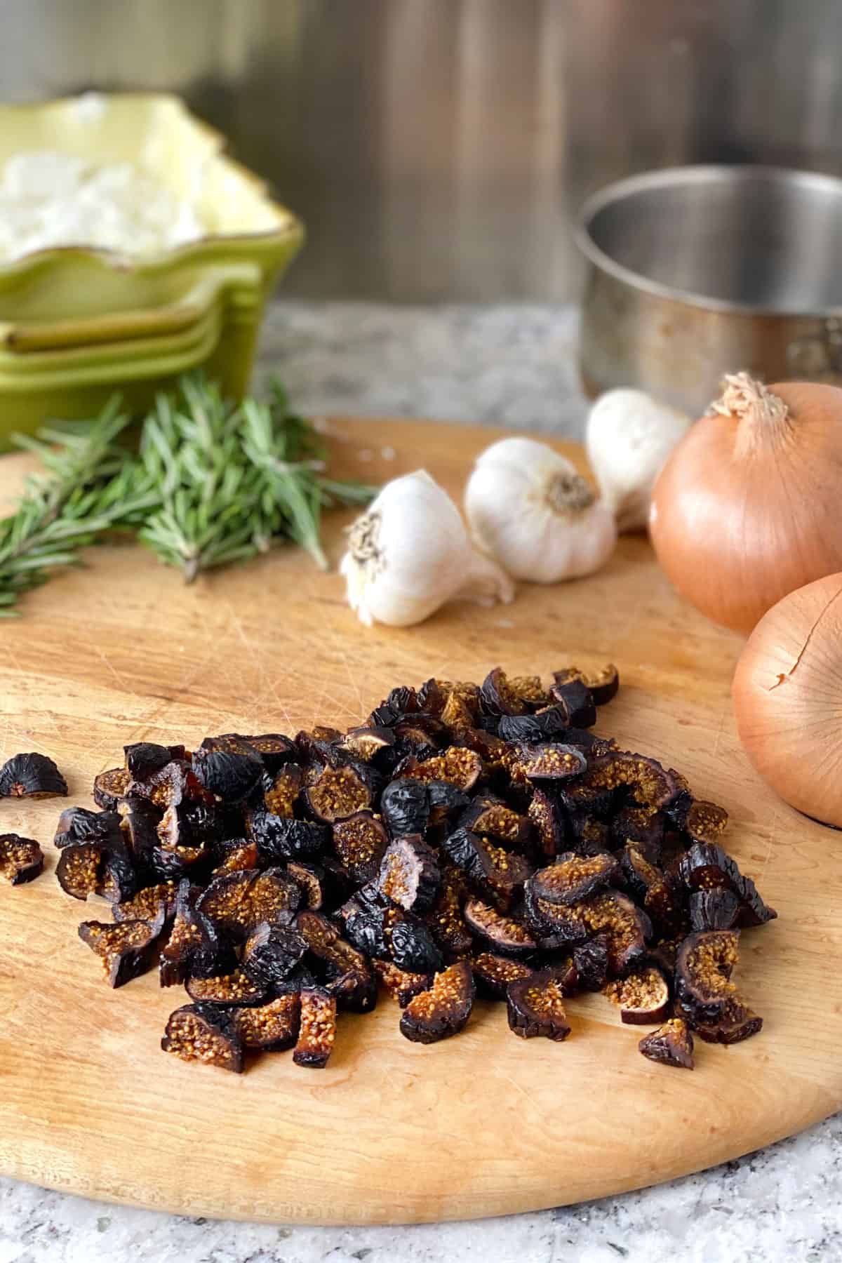 round cutting board with chopped mission figs, onions, garlic and rosemary