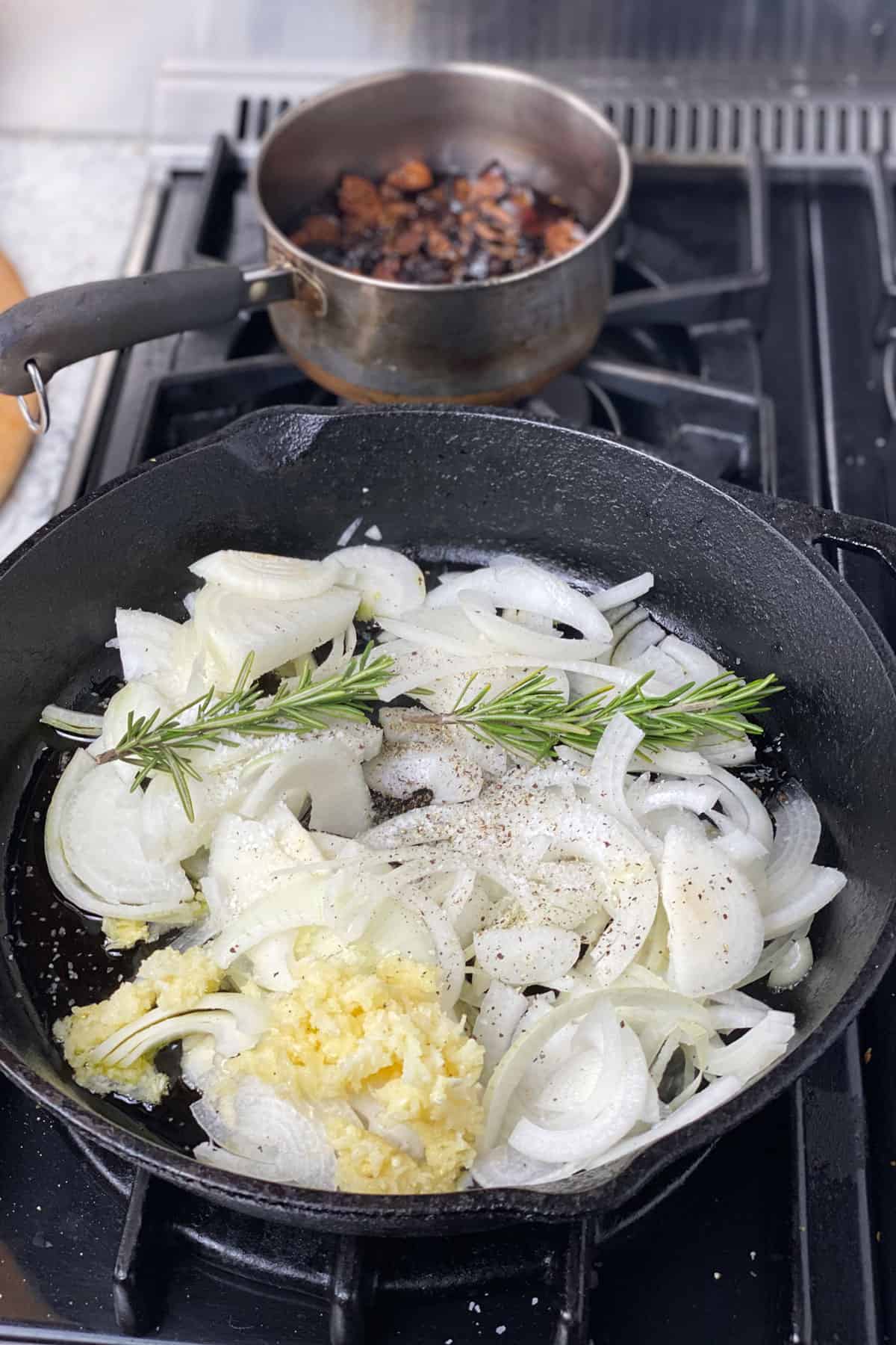 sliced onions and chopped garlic and a couple of rosemary sprigs in a cast iron skillet