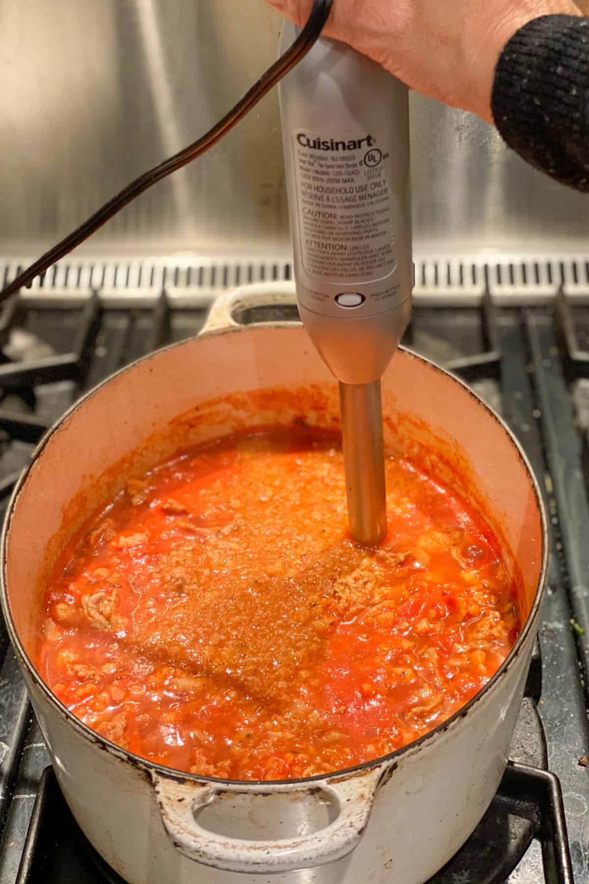 an immersion blender immersed in a Dutch oven, pureeing ground turkey soup.