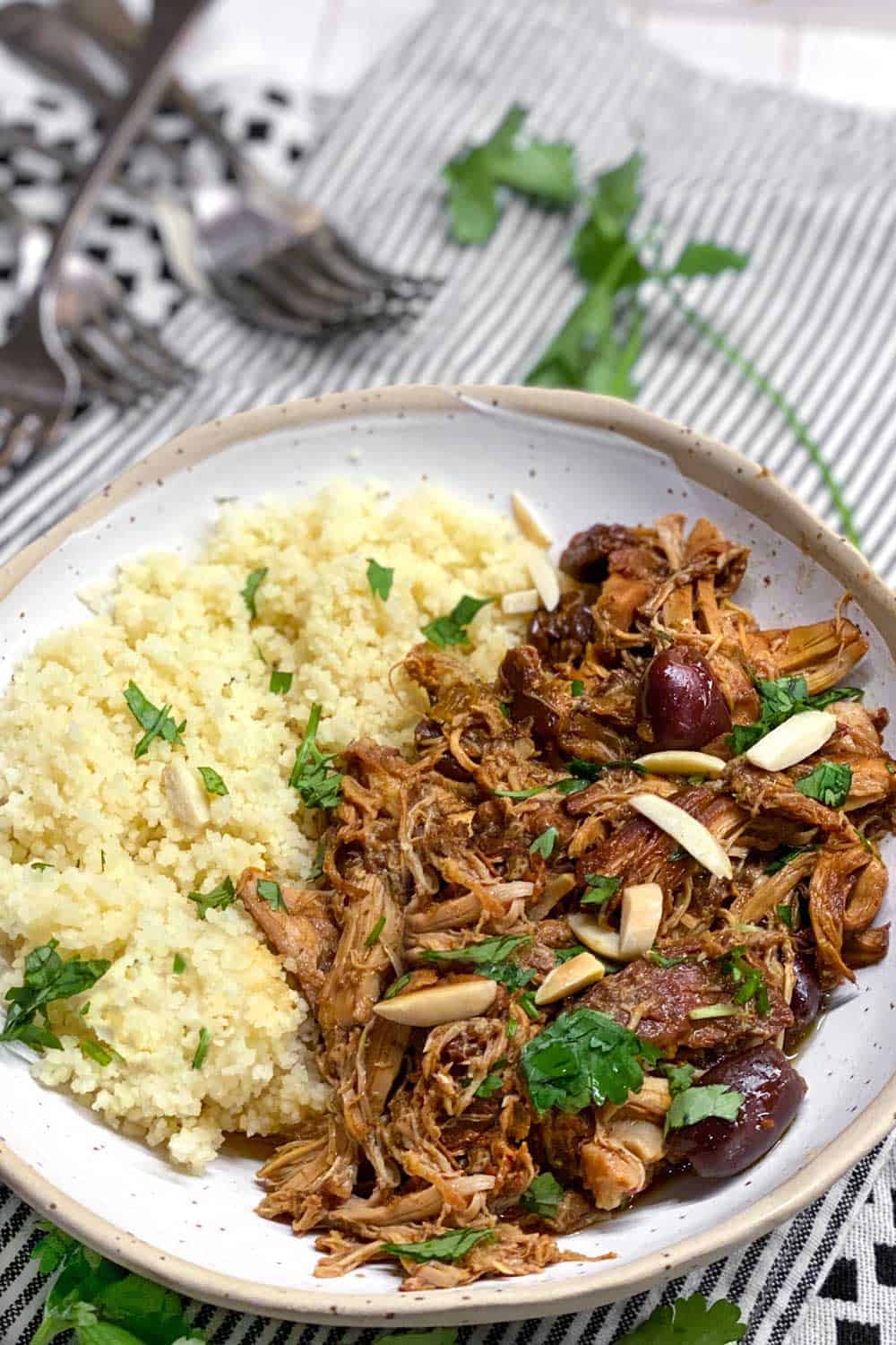 slow cooker chicken thighs and couscous in a white bowl on a black ad white checked dishcloth