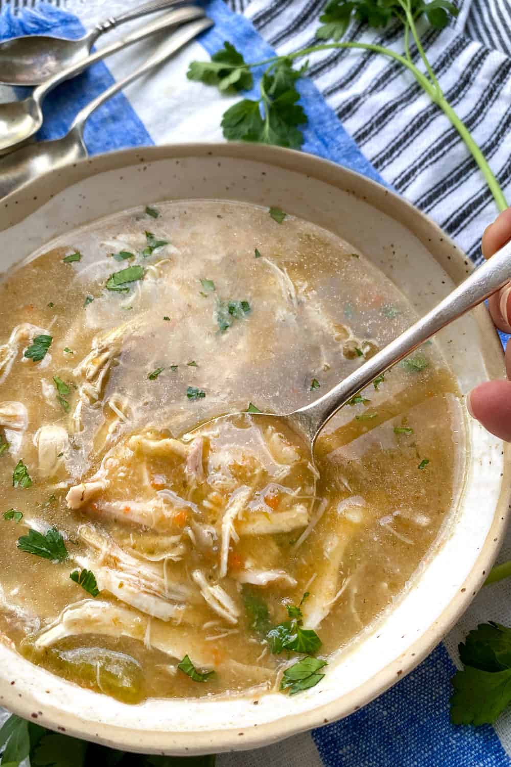 close up looking down into a white bowl filled with creamy chicken soup that has lots of shredded chicken in it.