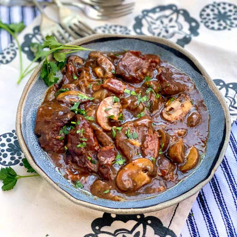 beef bourguignon in a blue bowl garnished with a sprig of parsley.