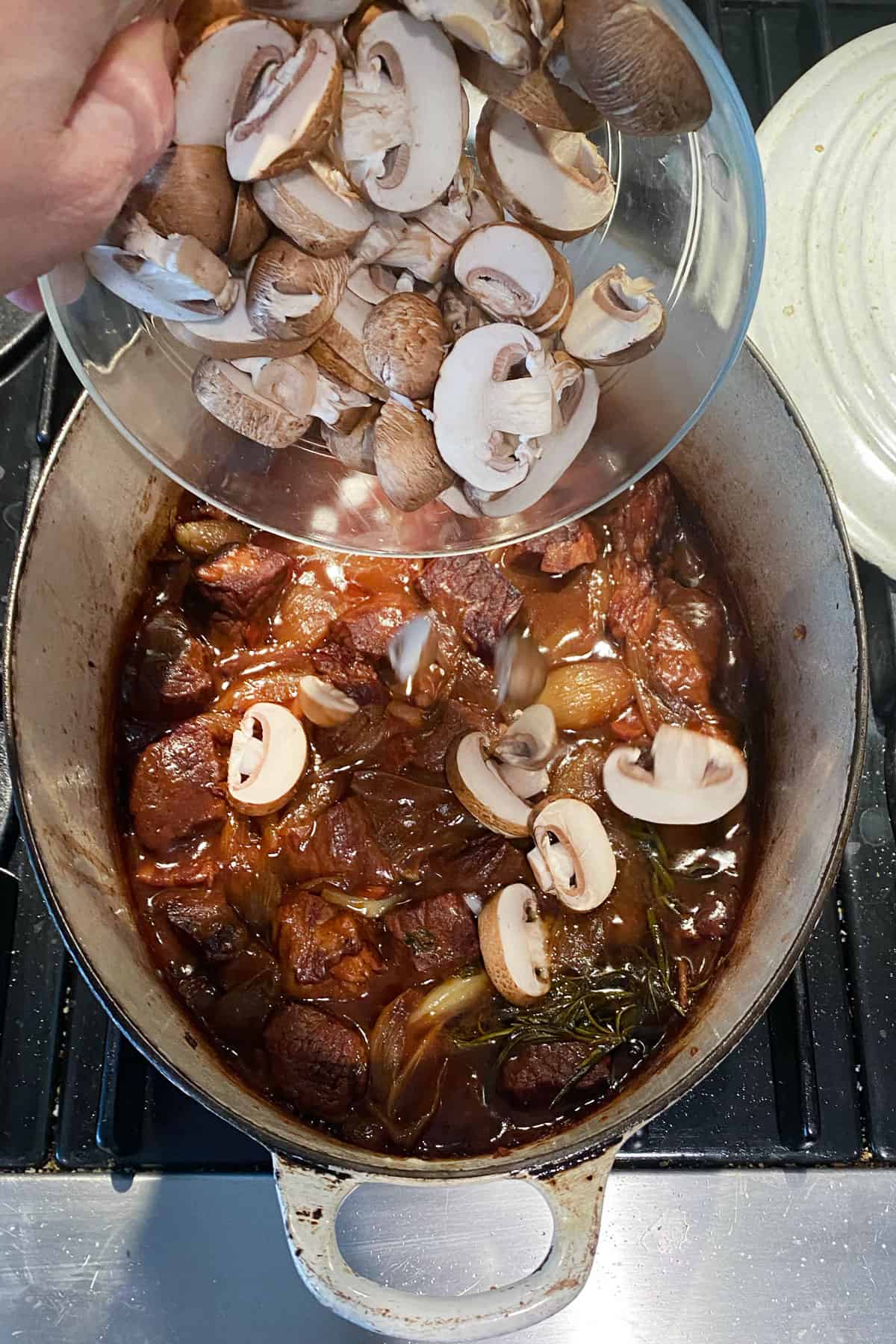 Sliced mushrooms being added to the stew pot.