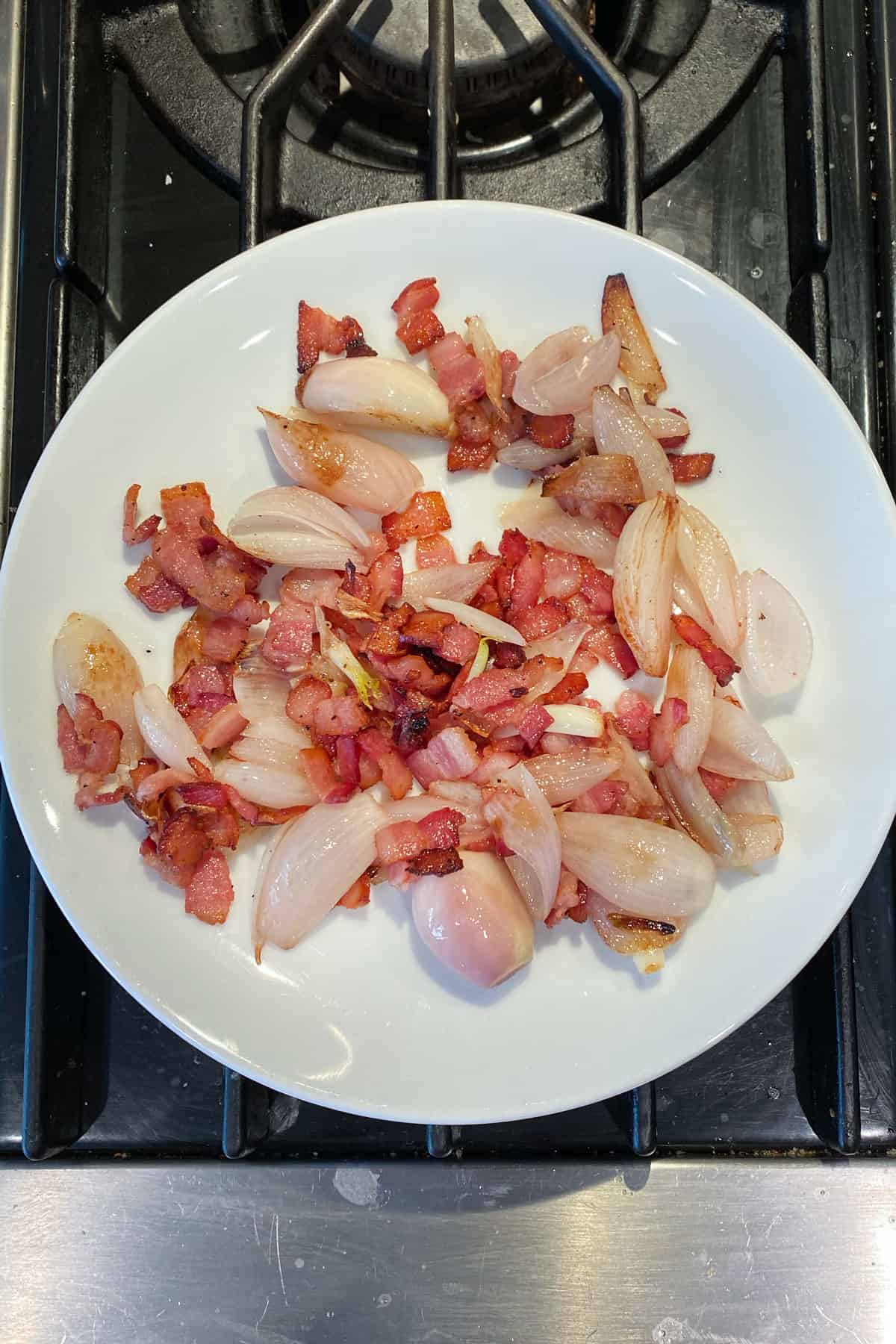 Sautéed shallots and bacon on a small plate.