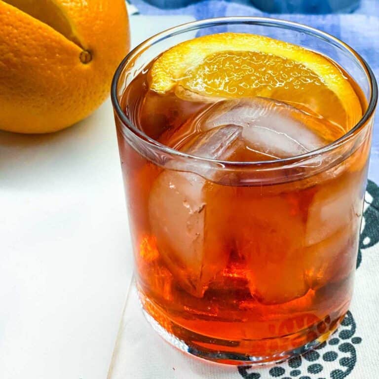 close up of a Negroni in a tumbler with ice and an orange wedge
