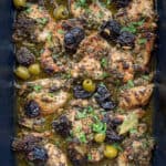 10 pieces of chicken Marbella in a roasting pan with prunes, green olives and a garnish of chopped parsley
