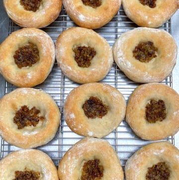 12 bialys on a wire rack on a stainless steel countertop