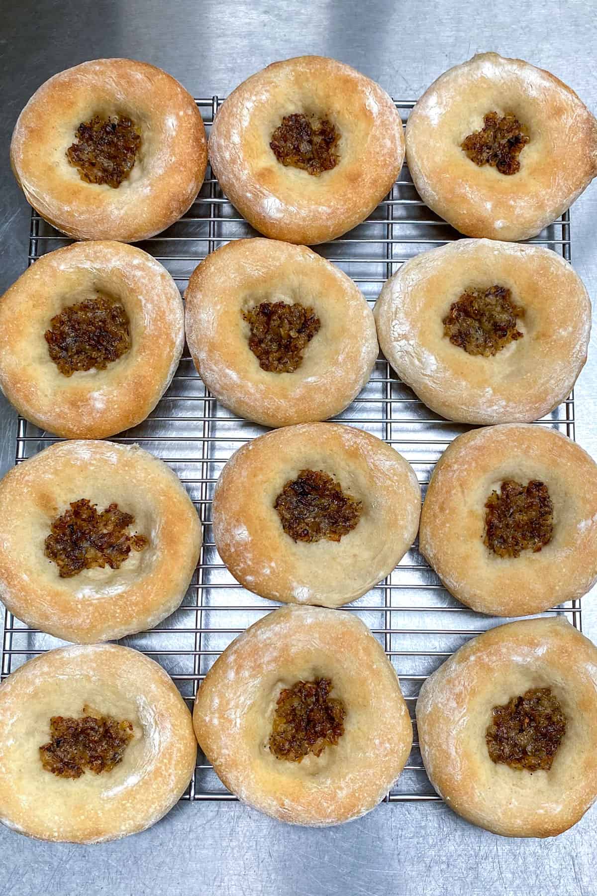 12 bialys on a wire rack on a stainless steel countertop