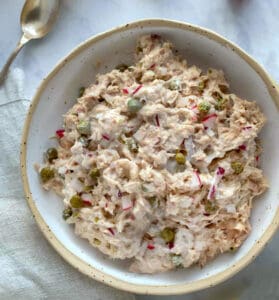 white bowl filled with healthy tuna salad, with flecks of radish, capers and red onion.