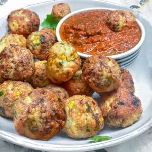 Turkey corn meatballs on a serving plate with a bowl of red pepper dip