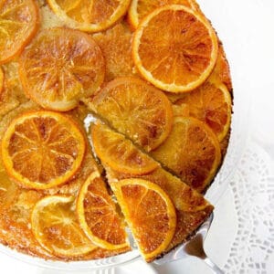orange vanilla upside down cake with a triangular slice cut and on a spatula