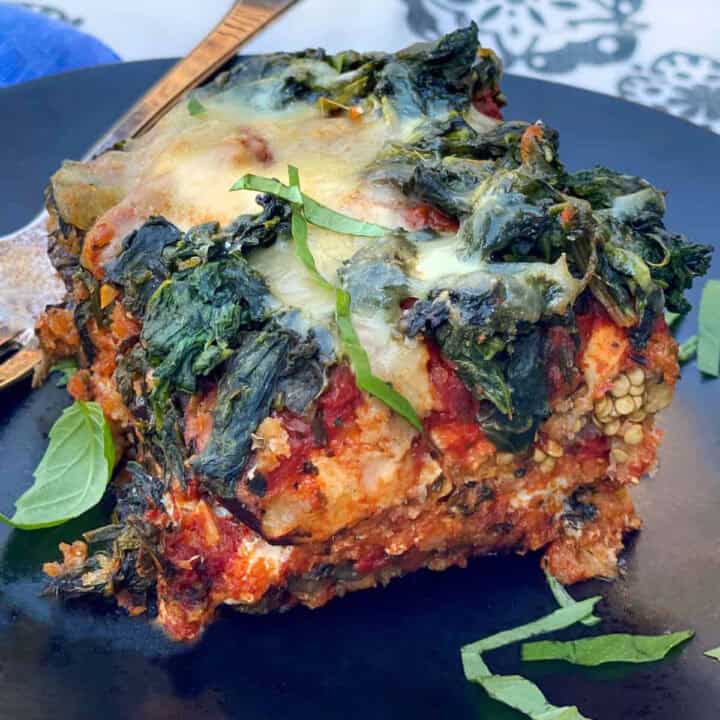 A slice of eggplant parmesan with spinach and cheese on top.
