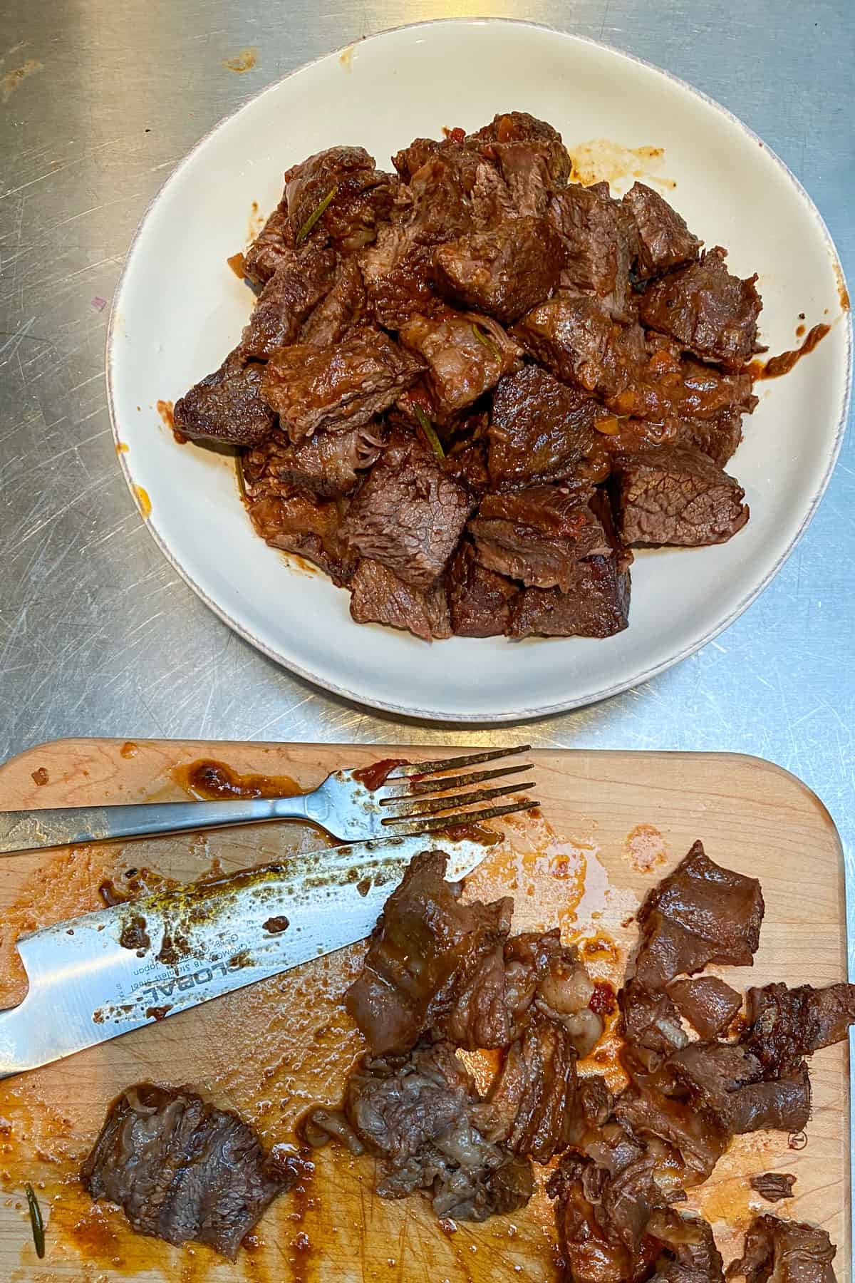 Bite-sized cubes of beef in a bowl with the cutting board nearby.