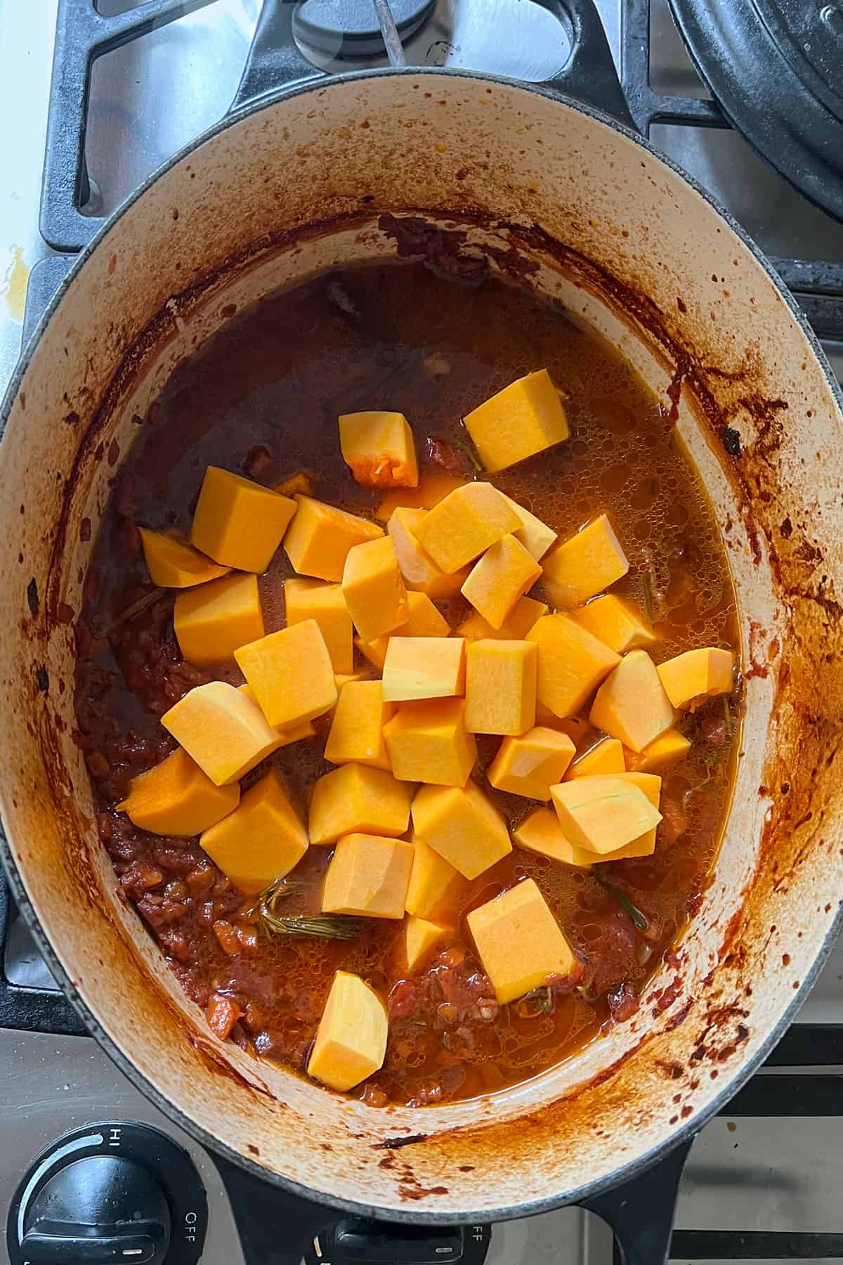 cubes of butternut squash on top of stew in a dutch oven.