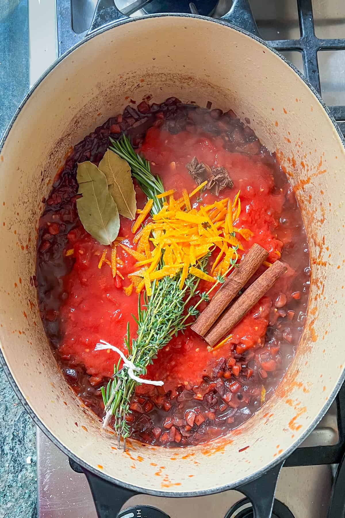 pureed tomatoes, herb bundle, cinnamon sticks, orange zest, bay heaves and star anise added to the stew pot.