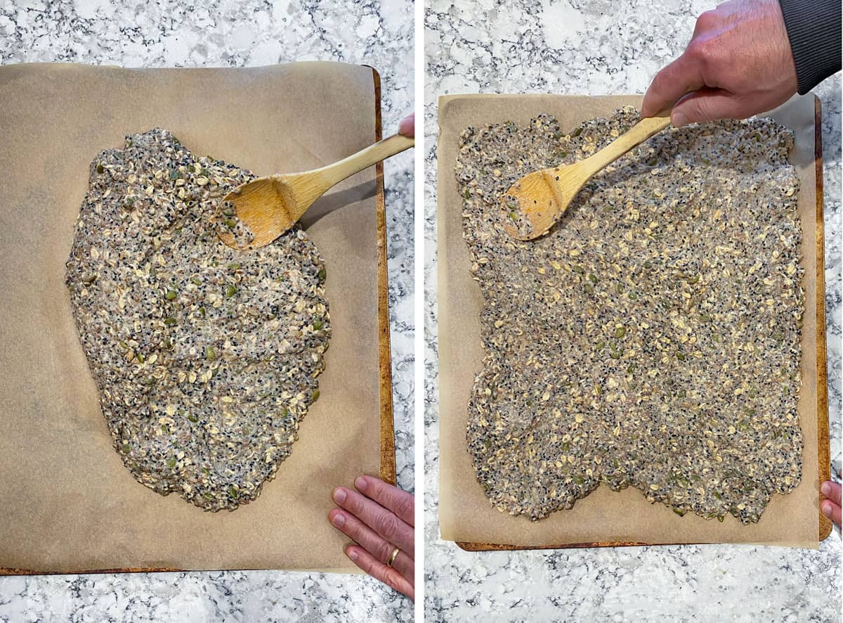 overhead shot of seeded cracker dough being spread out on a parchment lined baking tray, using the back of a wooden spoon