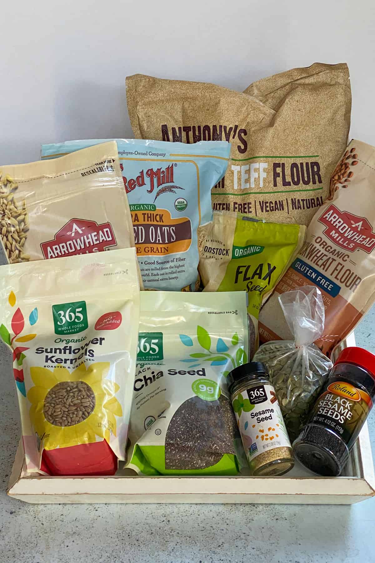 8 bags of different types of flour and seeds, all on a white tray