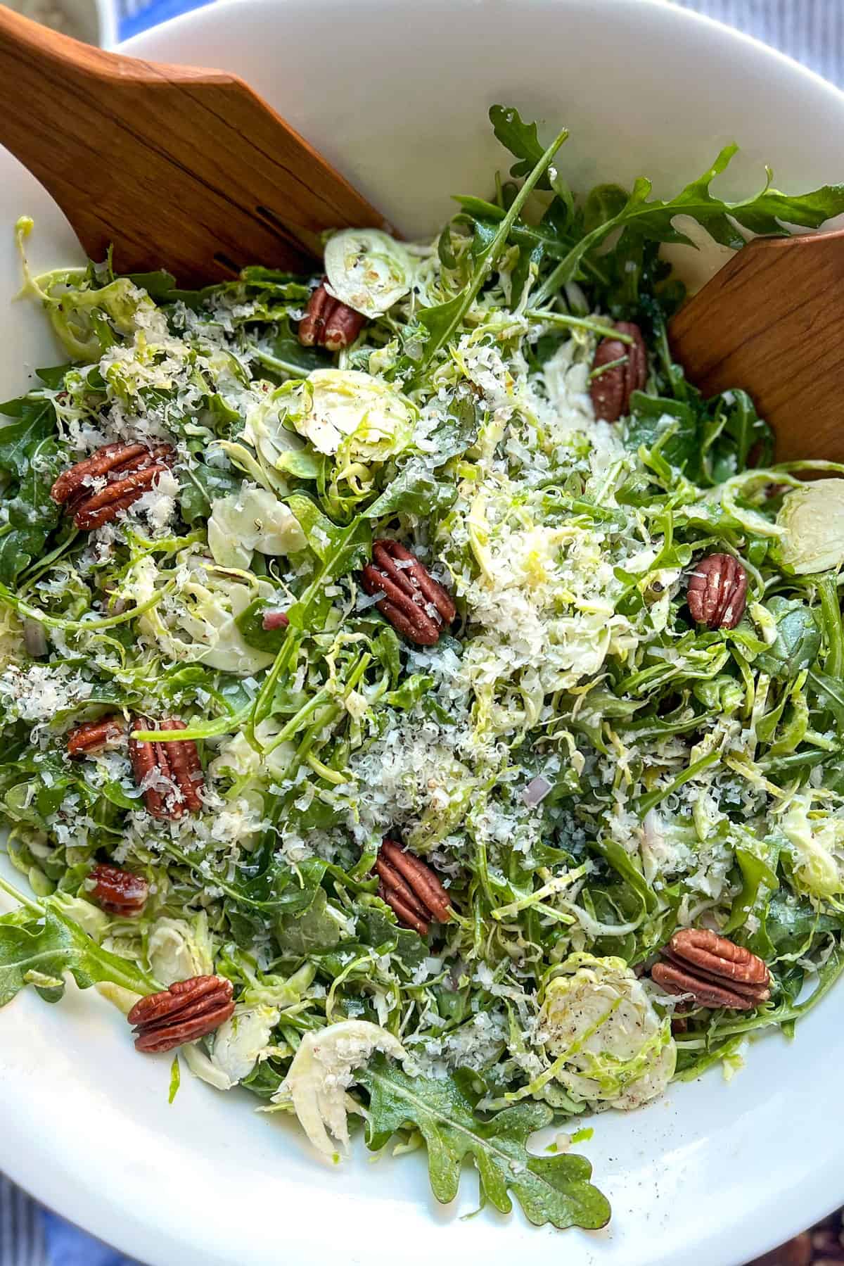 close up overhead shot of a shredded Brussels sprout and arugula salad with toasted pecans and grated parmesan cheese