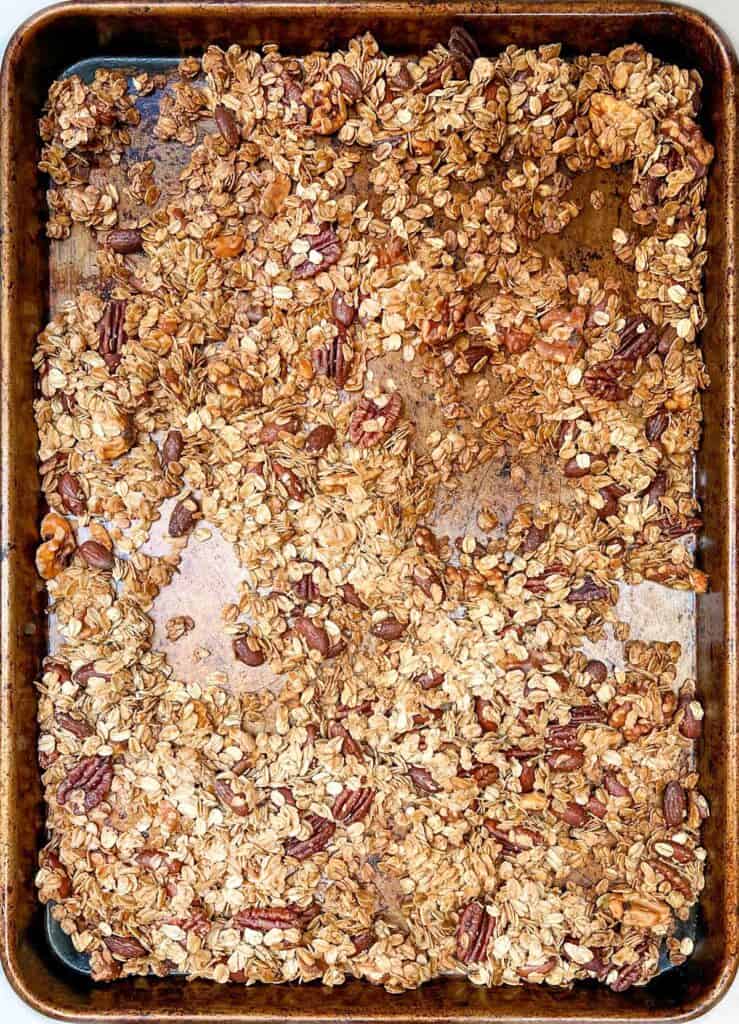 overhead shot of a rimmed baking sheet filled with nutty, golden, baked granola