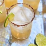 4 cocktails on a silver tray with limes