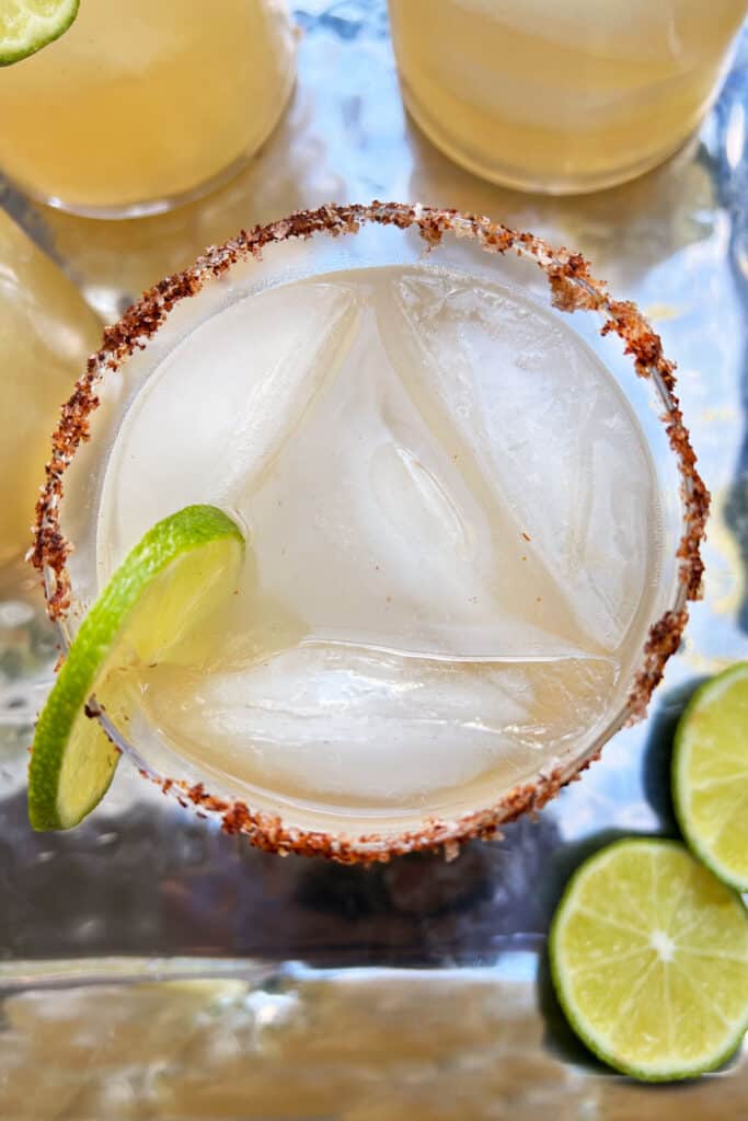 overhead shot of a bone crusher cocktail in an iced glass with a ring of lime on the glass and a chili salt rim.