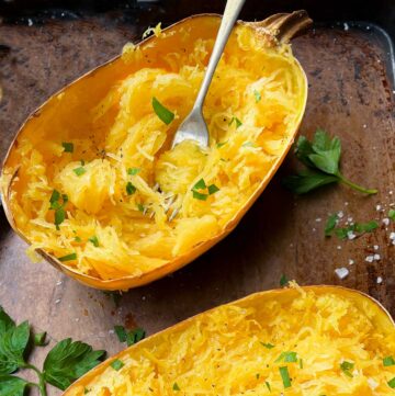 oven roasted spaghetti squash half on a sheet pan with a fork twirling the noodles