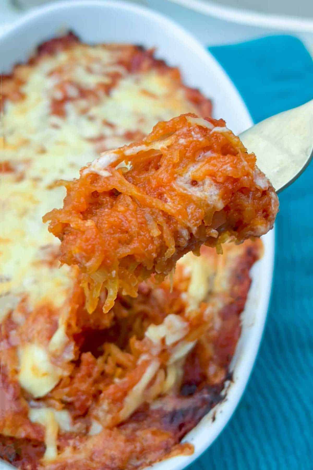 close up of a fork with tomatoey cheesy spaghetti squash twirled around its tines