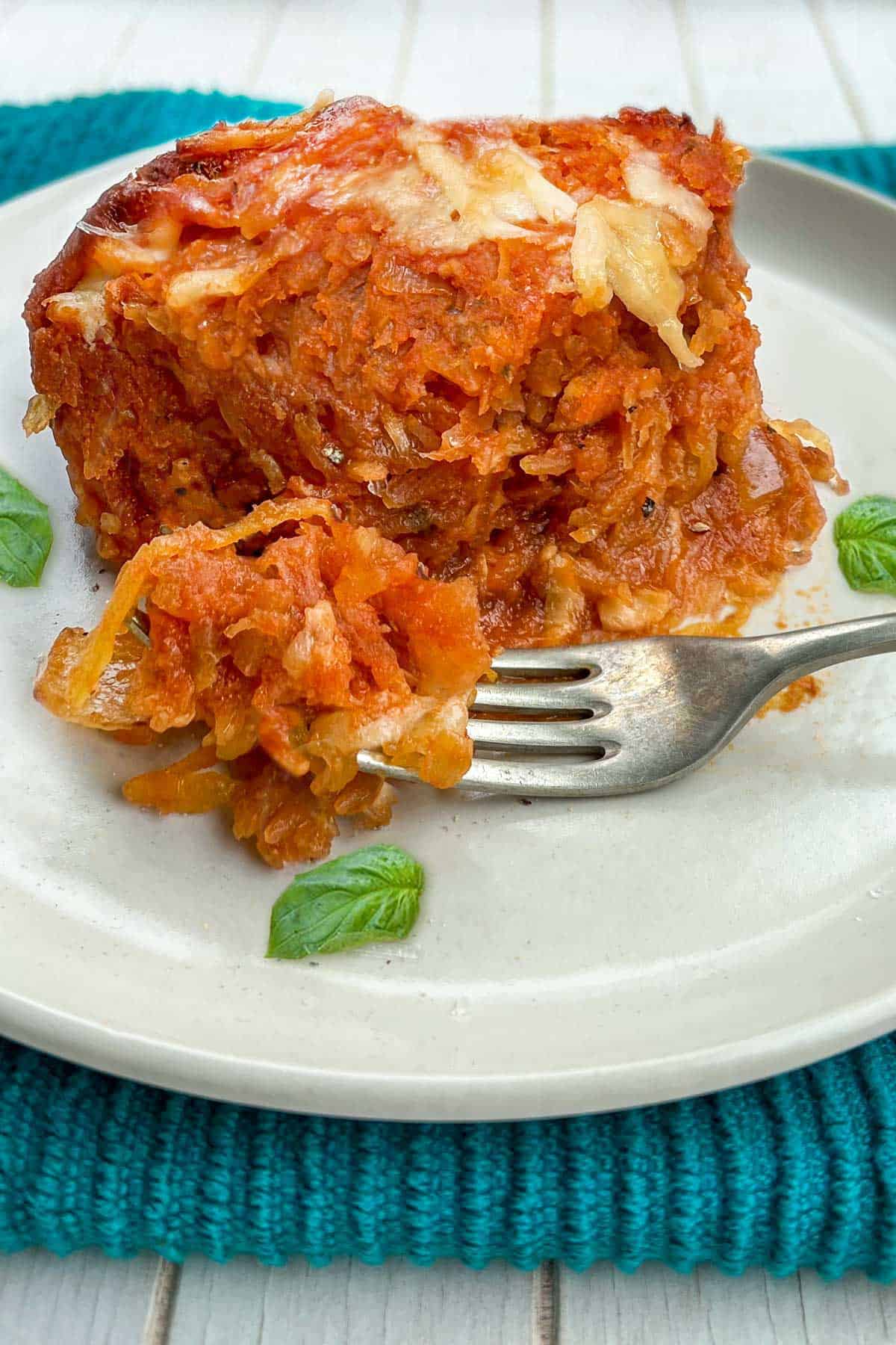 portion of spaghetti squash casserole on a white plate with a fork