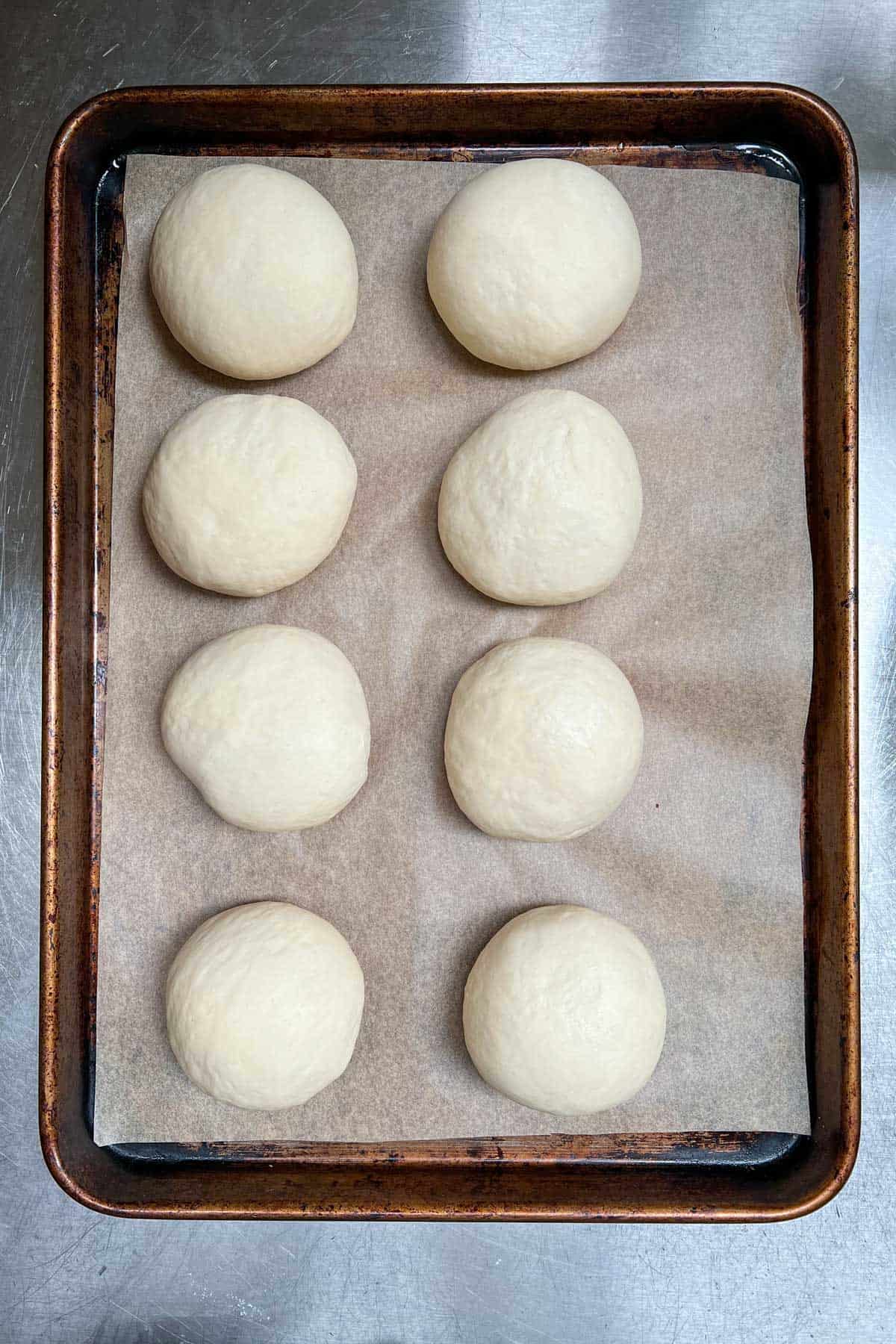 8 balls of dough on a parchment lined rimmed baking sheet