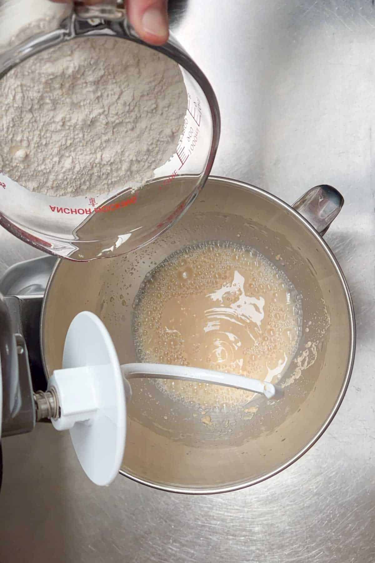adding flour to wet ingredients in the bowl of a stand mixer