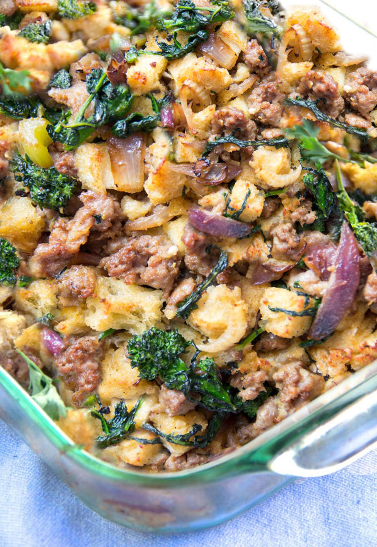 sausage stuffing with bits of broccoli rabe and red onion in a glass casserole