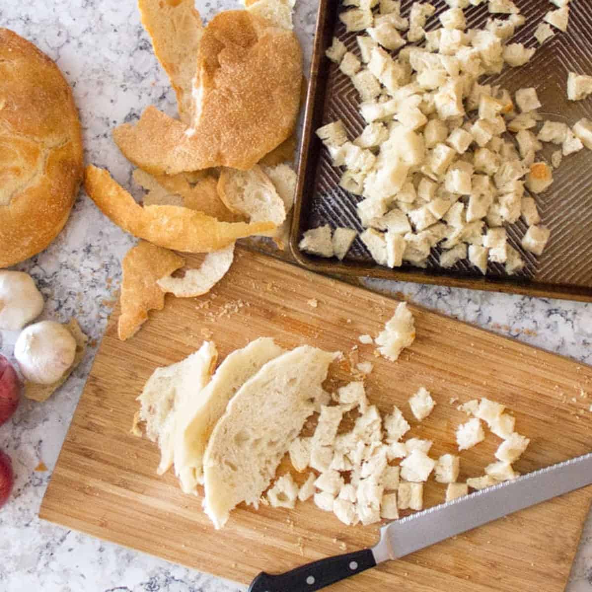 cutting Italian bread into cubes and putting it on a rimmed baking sheet.