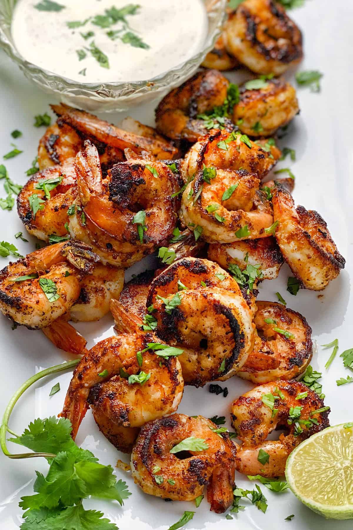 20 or so spice crusted sautéed shrimp on a white platter sprinkled with chopped cilantro, with a small bowl of remoulade dipping sauce in the corner.