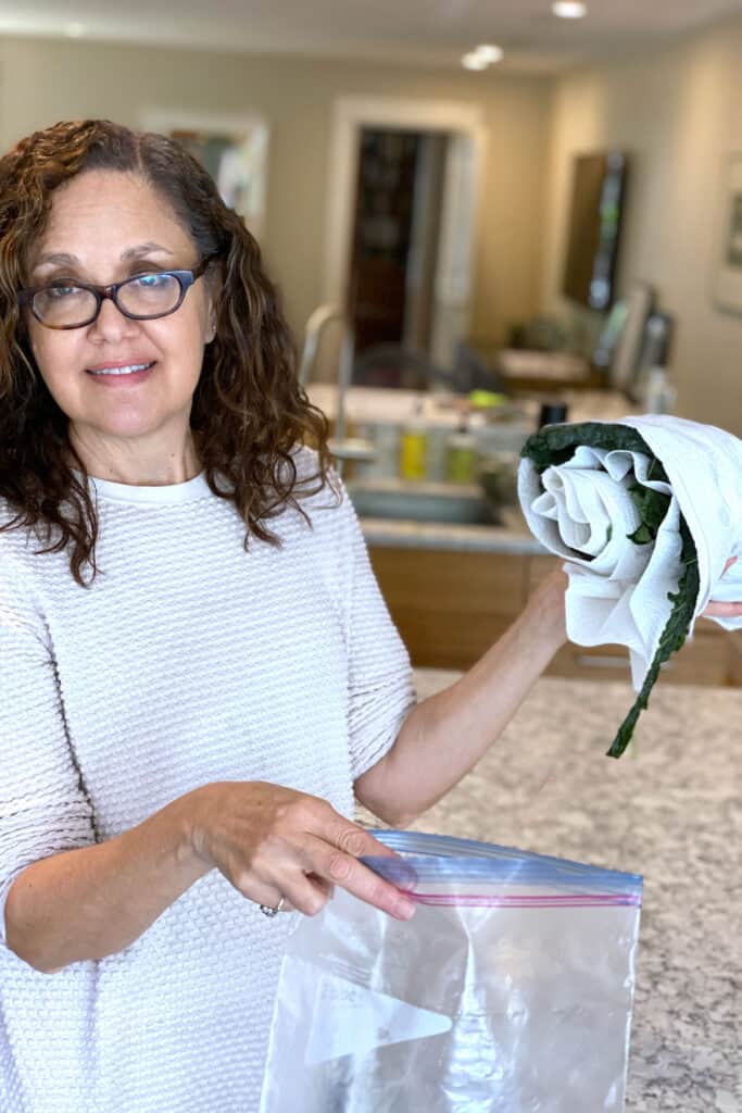 Lisa Goldfinger about to put a roll of kale leaves into a plastic baggie