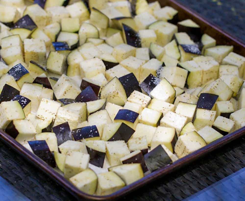salted eggplant cubes spread out in a rimmed baking sheet
