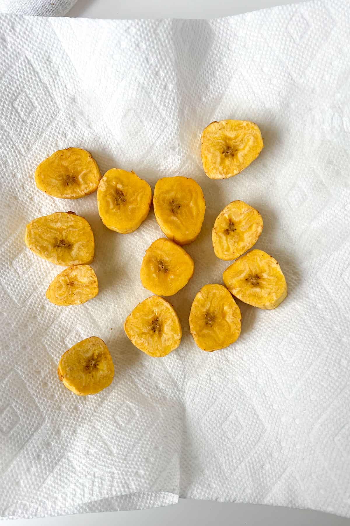 a dozen pieces of sliced fried green plantain draining on paper towels