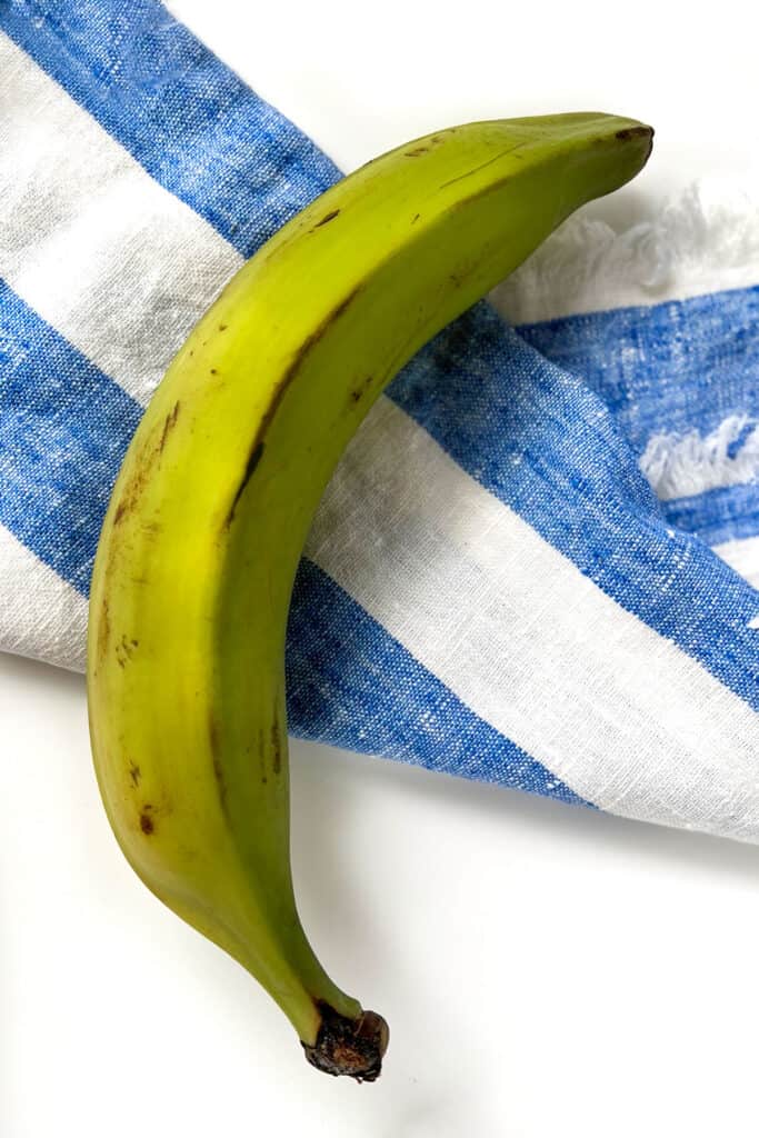 A green plantain on a striped cloth napkin