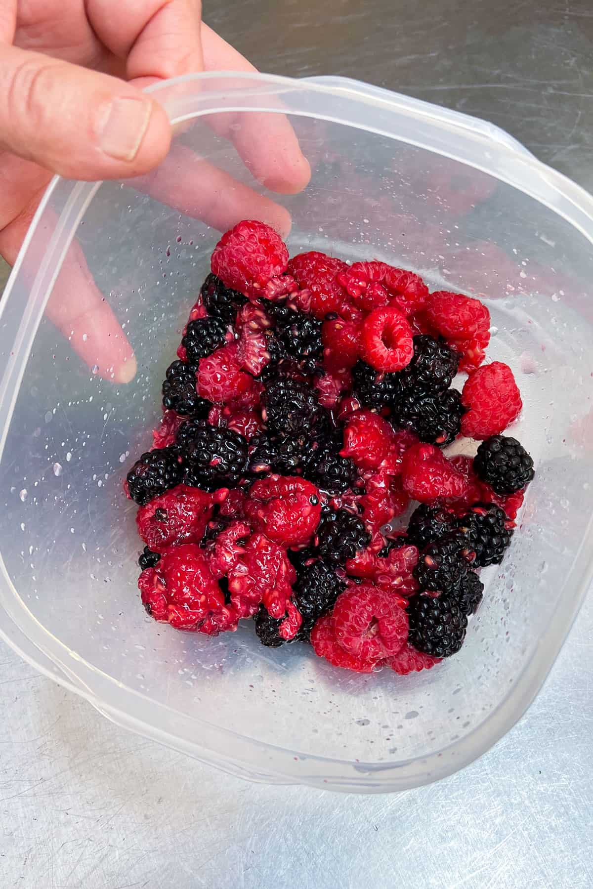 Bruised fresh blackberries and raspberries in a plastic container