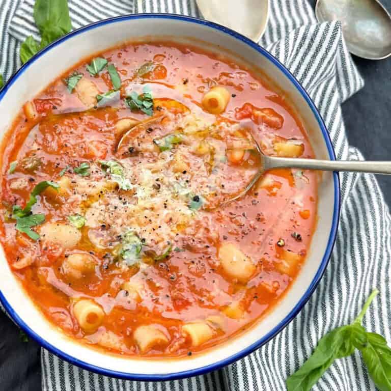 bowl of pasta e fagioli soup with tiny tubular pasta and cannellini beans, in thick broth, topped with grated parmesan cheese