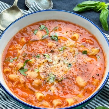 bowl of pasta e fagioli sprinkled with chopped basil and finely grated parmesan cheese