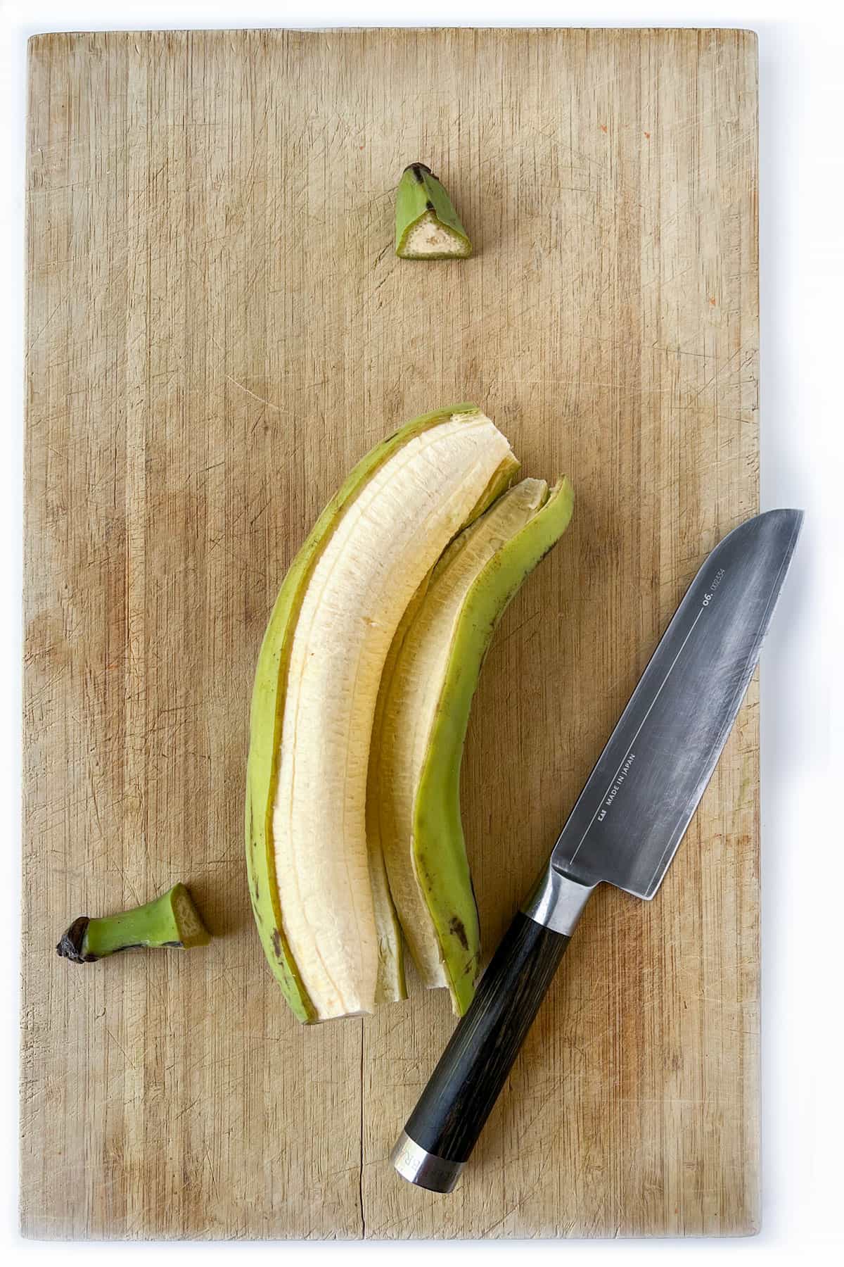 A green plantain with the skin peeled off and the ends snipped off